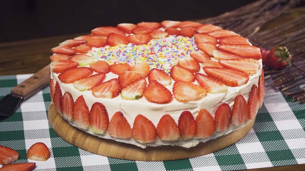 Strawberry Cream Cake Recipe, A soft sponge cake brushed with red wine, with buttercream frosting, then topped with sliced fresh strawberries..