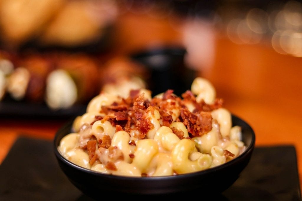 mac and cheese with bacon bits sprinkled on top in a black bowl