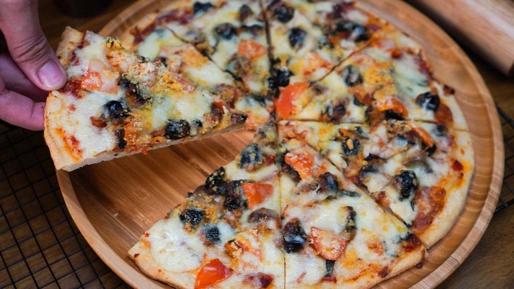 a man taking a slice of pizza