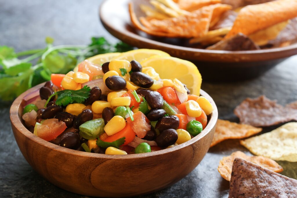 homemade black bean corn salsa with chips served in a wooden bowl