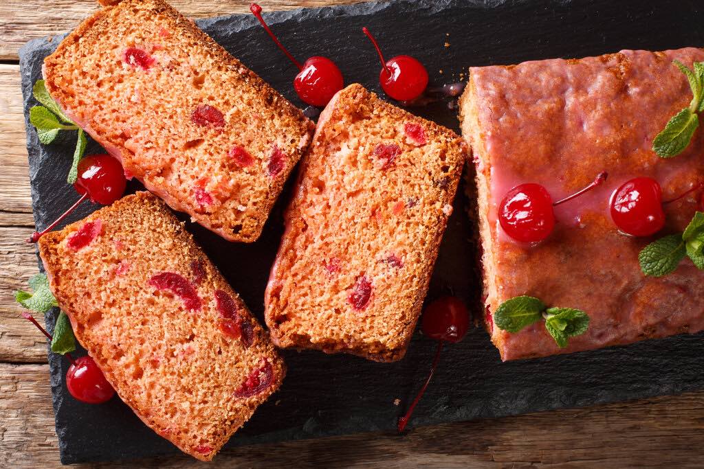 Sliced sweet bread with maraschino cherries, decorated with mint close-up on the table. Horizontal top view