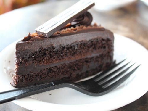 a slice of chocolate fudge cake with a fork on a plate