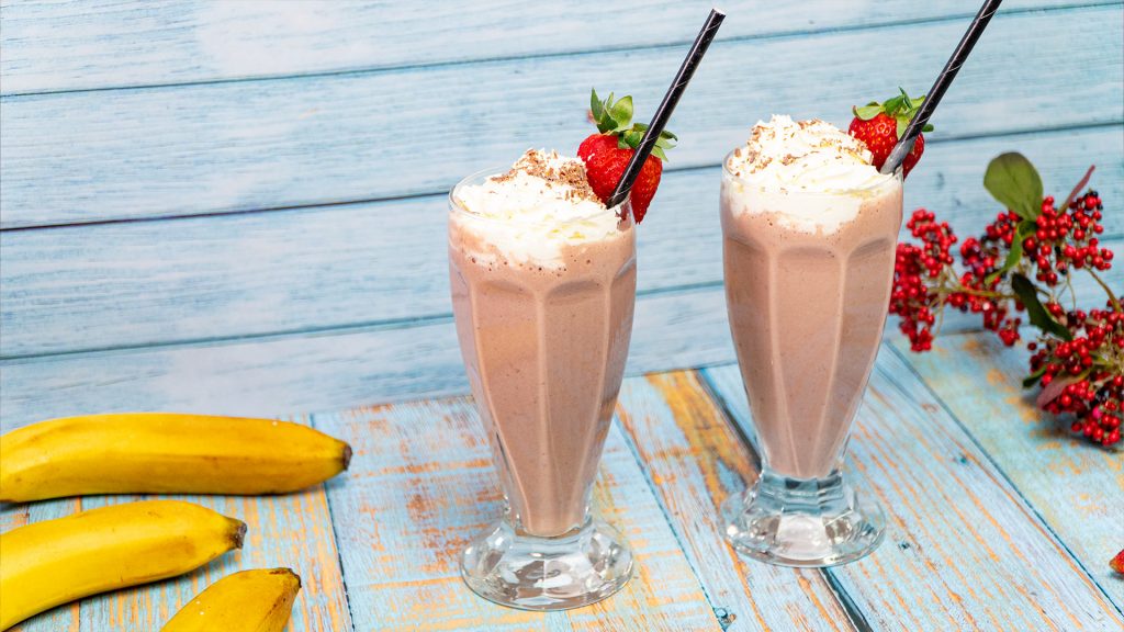 Banana, strawberry and chocolate milkshake in plastic cup with