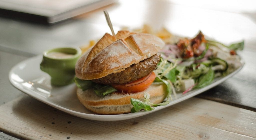 burger with a salad and other sides on a white plate