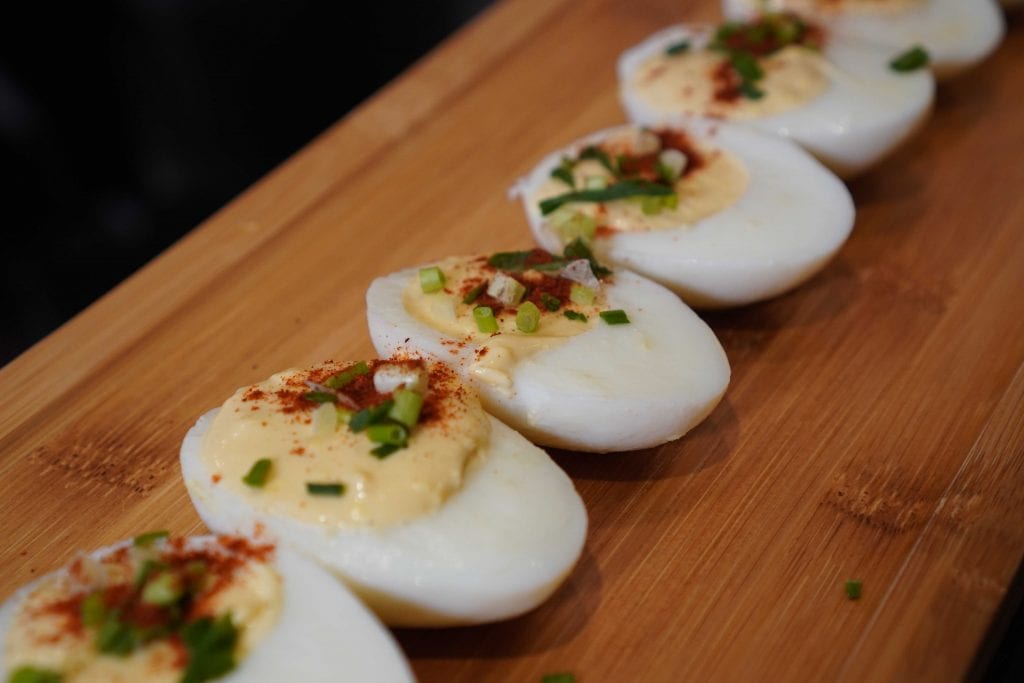 deviled eggs lined up on a wooden board