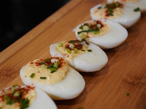 deviled eggs lined up on a wooden board