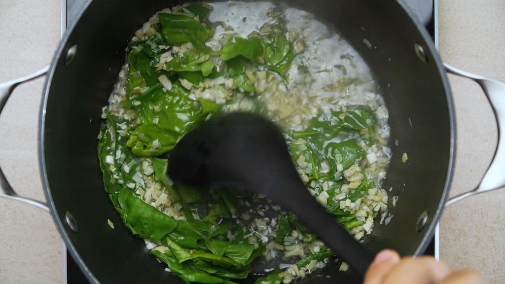 heating vegetable broth with fresh spinach, chopped artichoke hearts, and garlic
