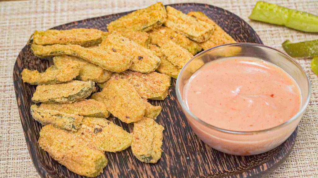 Oven Fried Dill Pickles Recipe, Fried dill pickles coated with cornmeal, served with ketchup-mayo dipping sauce, and on brown wooden plate