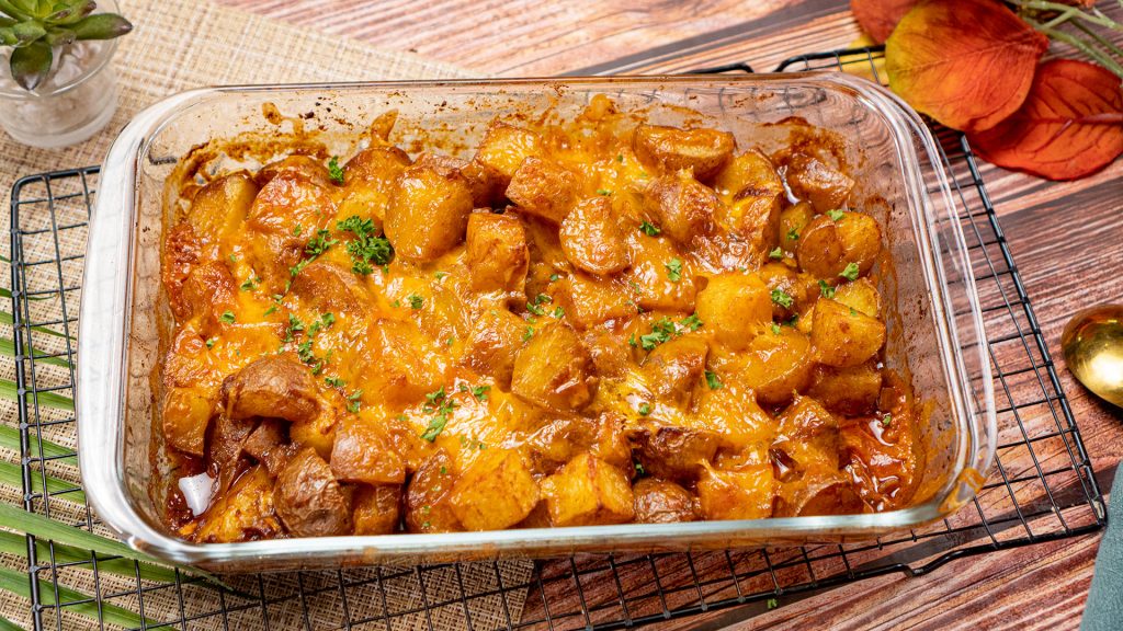 Spicy Roasted Potatoes Recipe, Roasted potatoes topped with melted cheddar cheese and chopped parsley is served on a baking casserole