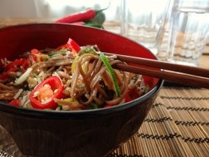 soba noodles mixed with vegetables and cut chilli peppers in a bowl