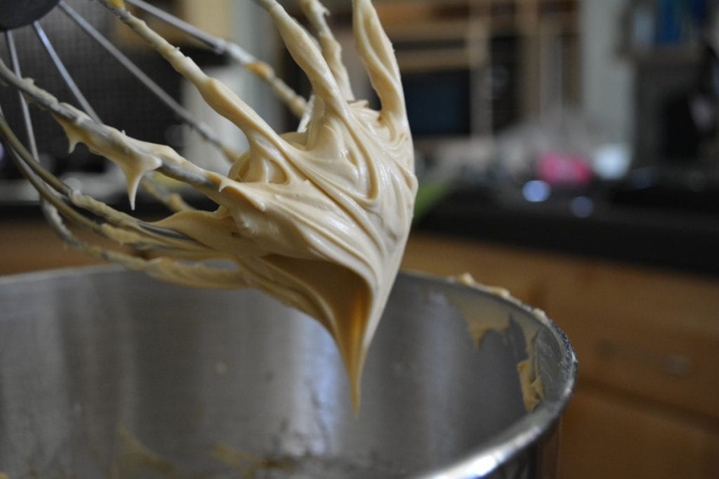 frosting or icing dripping from a whisk into a bowl