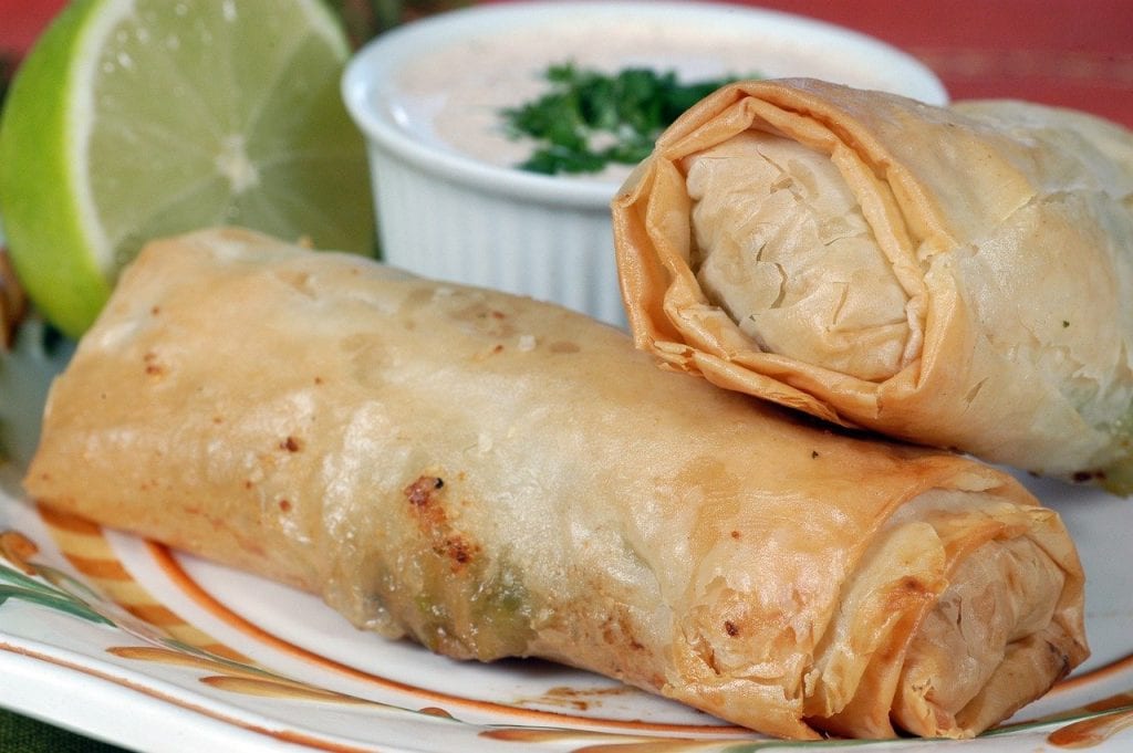 fried egg rolls with a dipping sauce and half a lime in the background