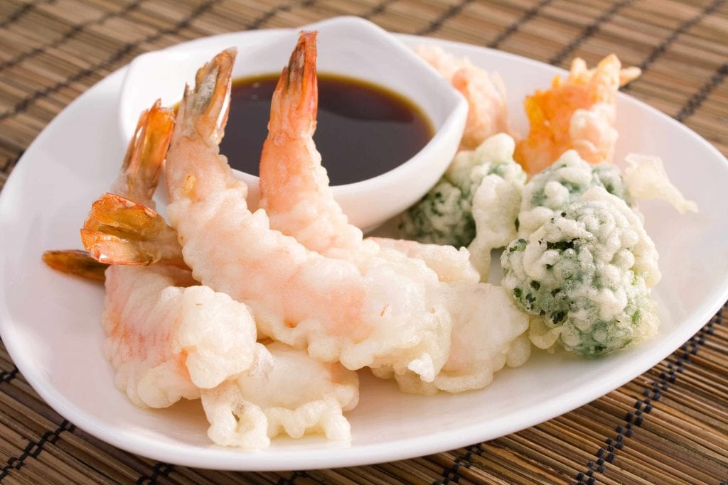 mixed tempura on a white dish with a saucer of soy sauce