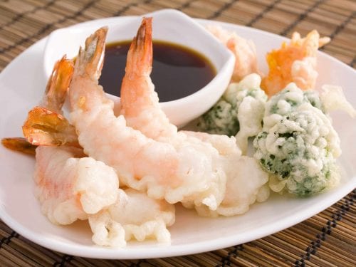 mixed tempura on a white dish with a saucer of soy sauce