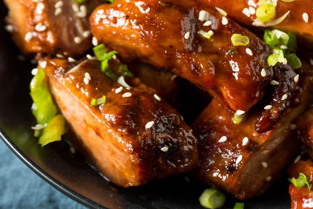 closeup bbq ribs garnished with chopped green onions and sesame seeds