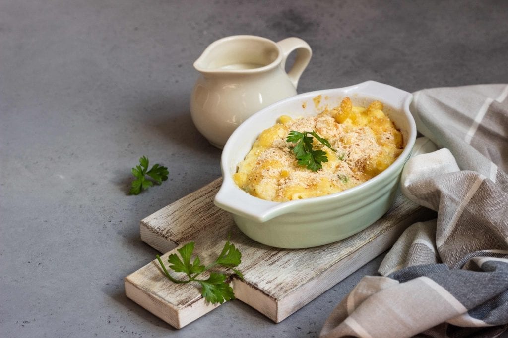 pasta casserole with peas and covered with breadcrumbs in a casserole dish against a grey background