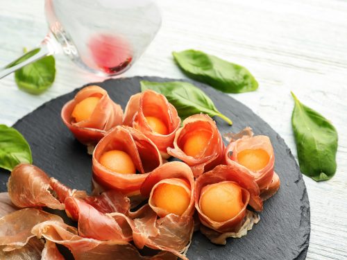 honeydew melon are wrapped in prosciutto and fresh mint