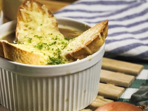 Panera French Onion Soup Recipe (Copycat) - Light soup made of caramelized onions and wine-infused beef broth with crispy baguette croutons and torched gruyere or emmental cheese on top on baked in the oven on a ramekin