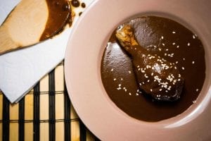 a single chicken drumstick covered in mole sauce