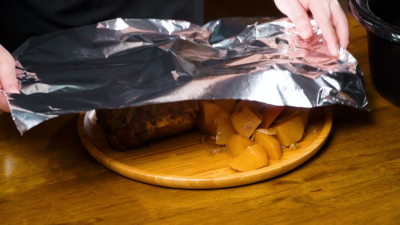 covering pork roast and vegetables with foil