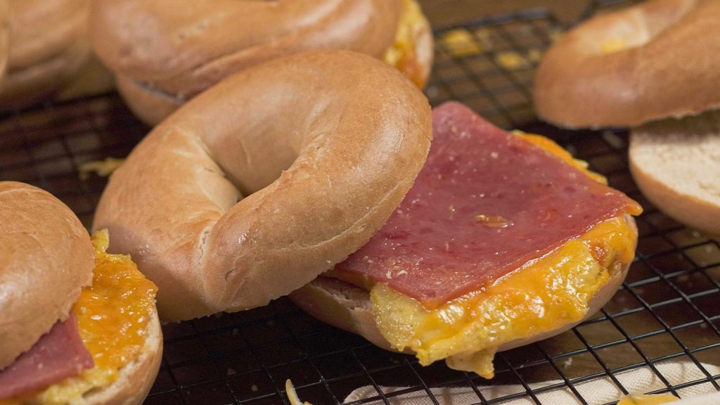 McDonald’s-Inspired Breakfast Sandwich Recipe, Bagel cut in half with cheese, ham, and scrambled eggs in the middle to form a sandwich