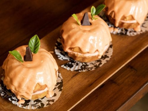 Jack-O-Lantern Pumpkin Bundt Cake Recipe, Mini pumpkin bundt cakes with vanilla frosting, topped with assorted chocolates