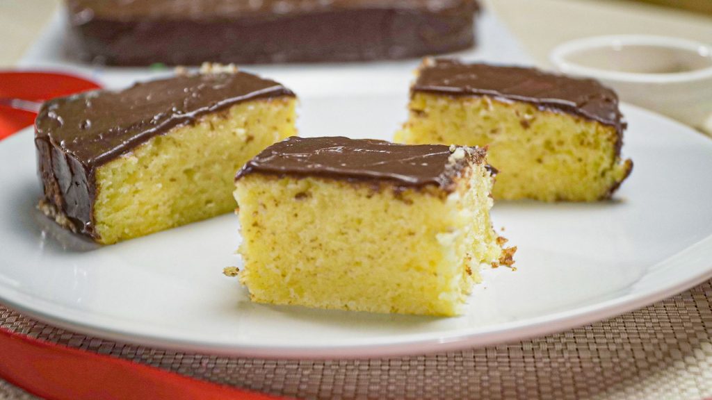 Buttery Vanilla Cake Recipe, Vanilla cake topped with chocolate frosting served on white plates