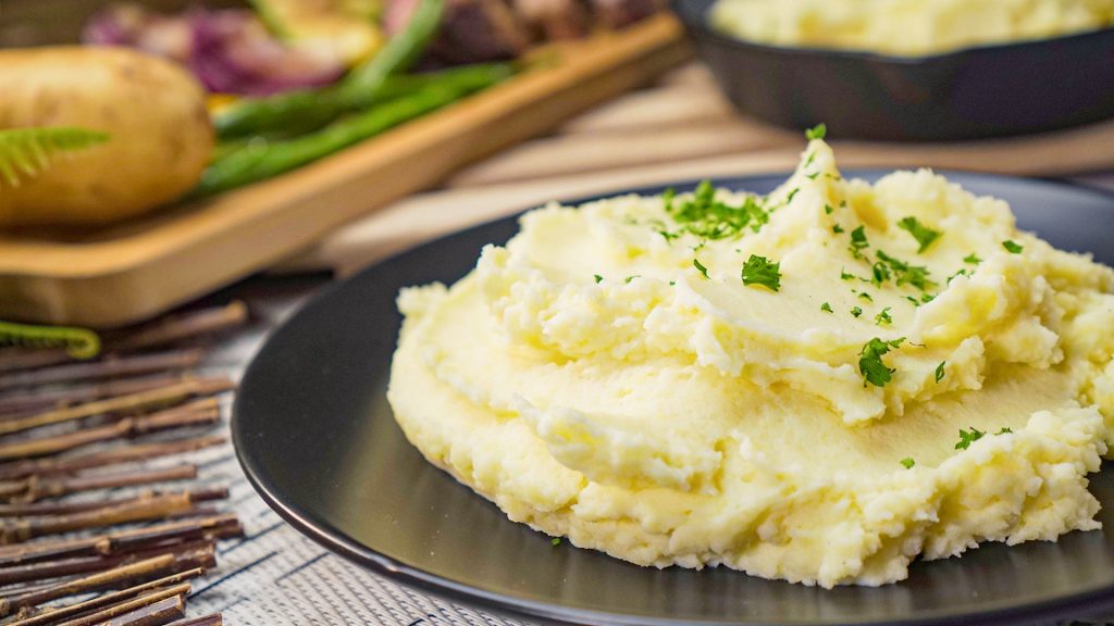 Crockpot Mashed Potatoes Recipe, Mashed potatoes topped with parsley and served on a black plate