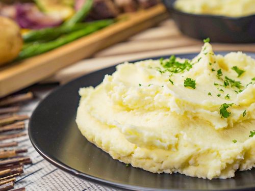 Crockpot Mashed Potatoes Recipe, Mashed potatoes topped with parsley and served on a black plate