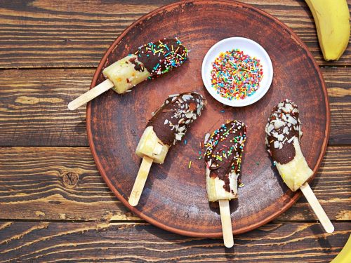 dessert, frozen bananas in chocolate on a stick on a brown clay plate, tropical desserts, party