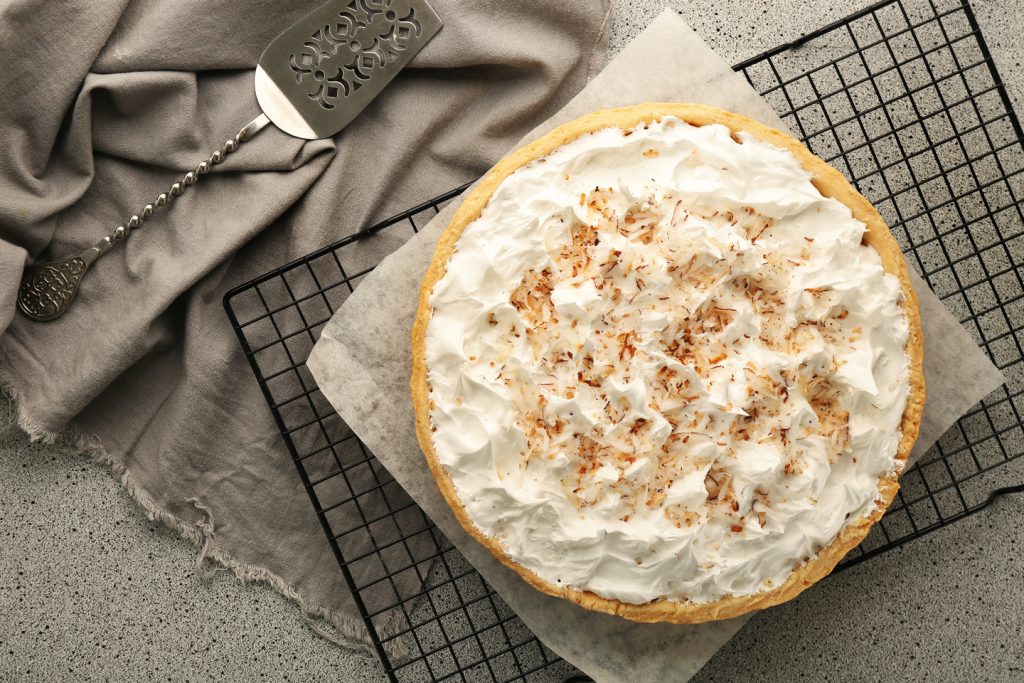 Grid with delicious coconut cream pie on grey table