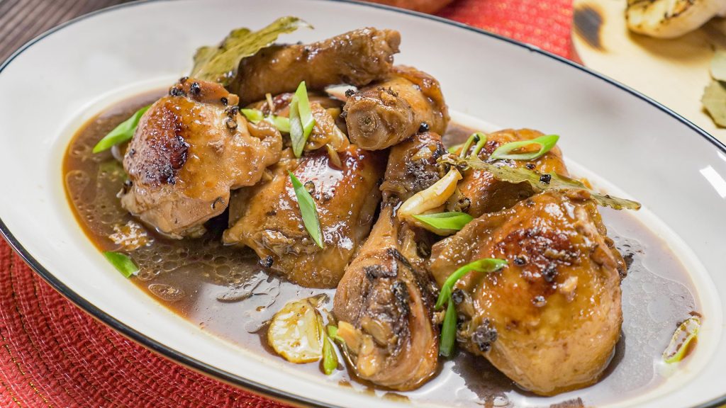 Filipino Adobo Chicken Recipe, Chicken stewed in soy sauce topped with spring onions and served on white serving plate