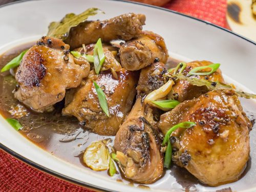 Filipino Adobo Chicken Recipe, Chicken stewed in soy sauce topped with spring onions and served on white serving plate