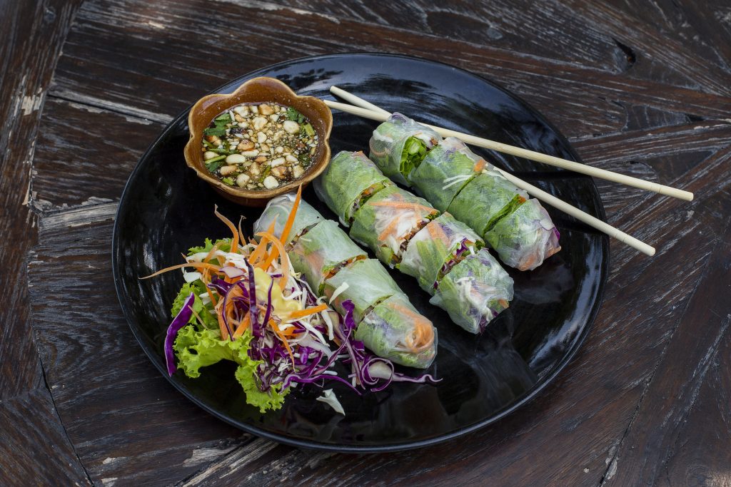 fresh vietnamese spring rolls, veggies, and nuoc cham on a black plate