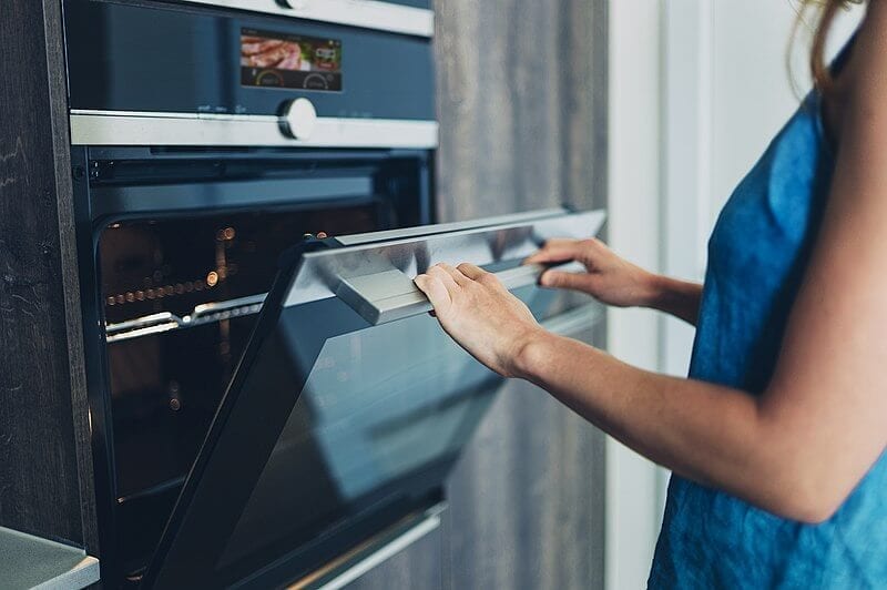 women reheating fried chicken in oven