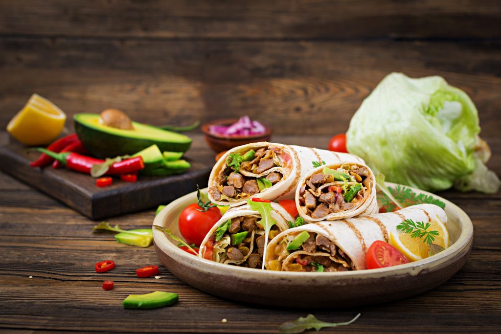 Burritos wraps with beef and vegetables on a wooden background. Beef burrito , mexican food. Healthy food background. Mexican cuisine.