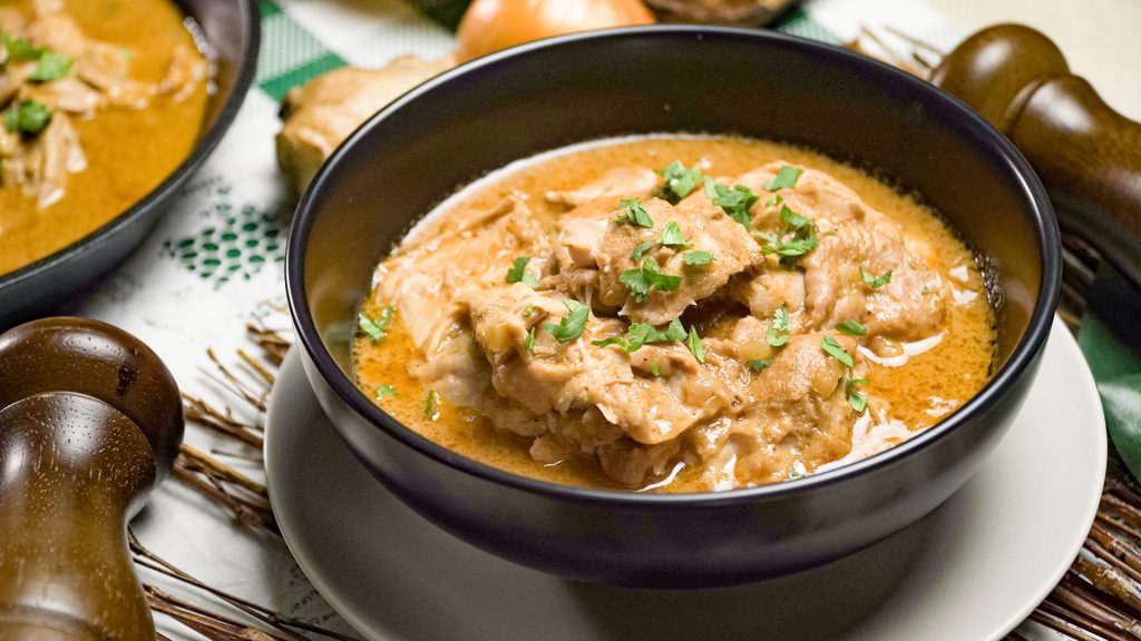 Slow Cooker Butter Chicken Recipe, Butter chicken with cilantro on top in a black bowl