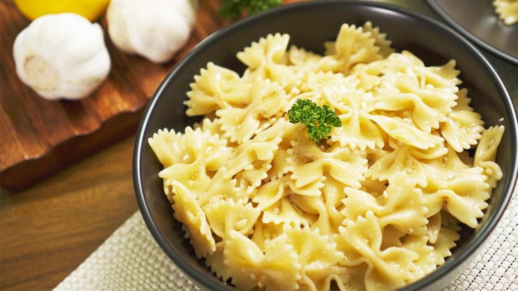 buttery-garlic-bow-tie-pasta-recipe firm and tender bow tie or farfalle pasta noodles with garlic butter sauce with a squeeze of lemon and garnished with parsley