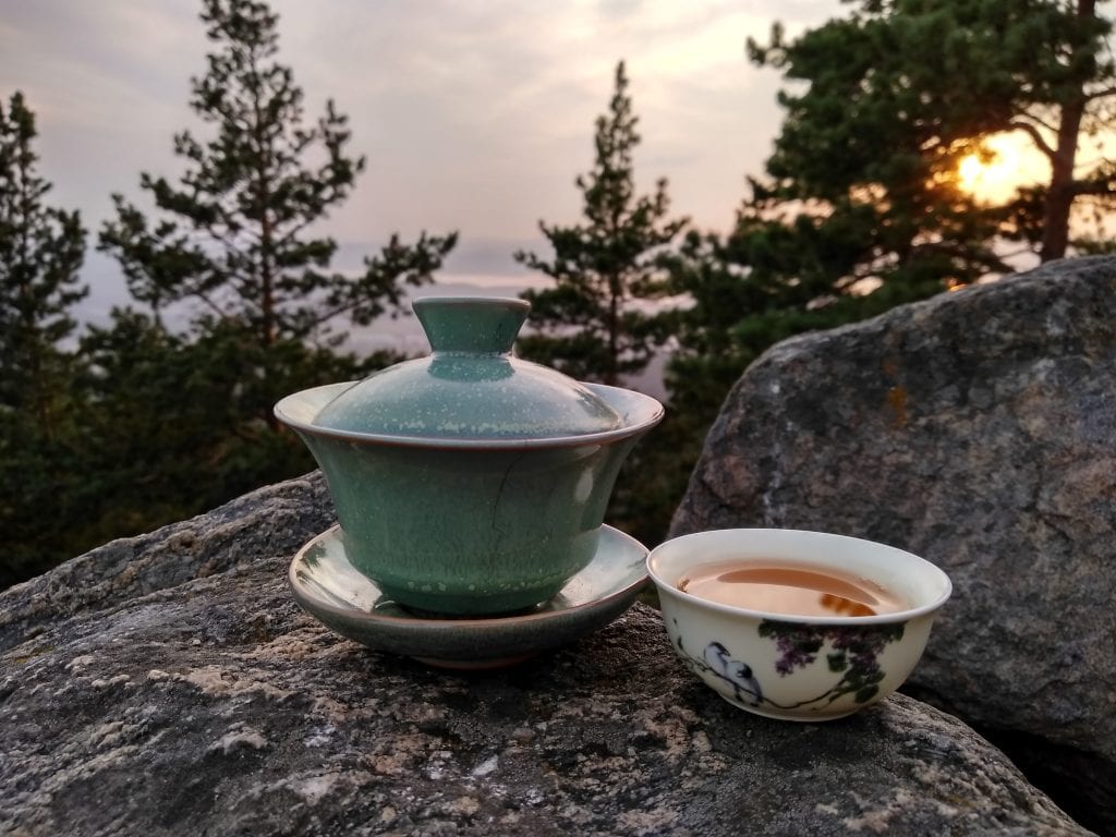 Chinese Tea: Surprising Benefits and 7 Famous Types to Try, teacup filled with tea and a gaiwan or small lidded bowl.