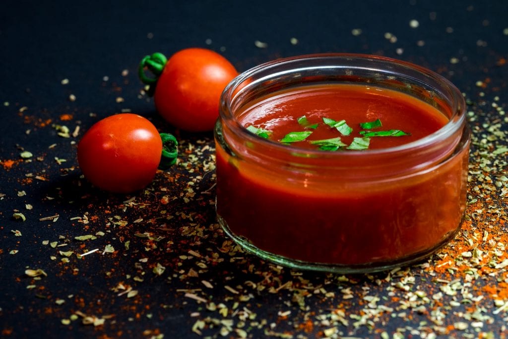 Arby's Sauce homemade ketchup-roast beef sauce on a storage jar, fresh tomatoes in the background