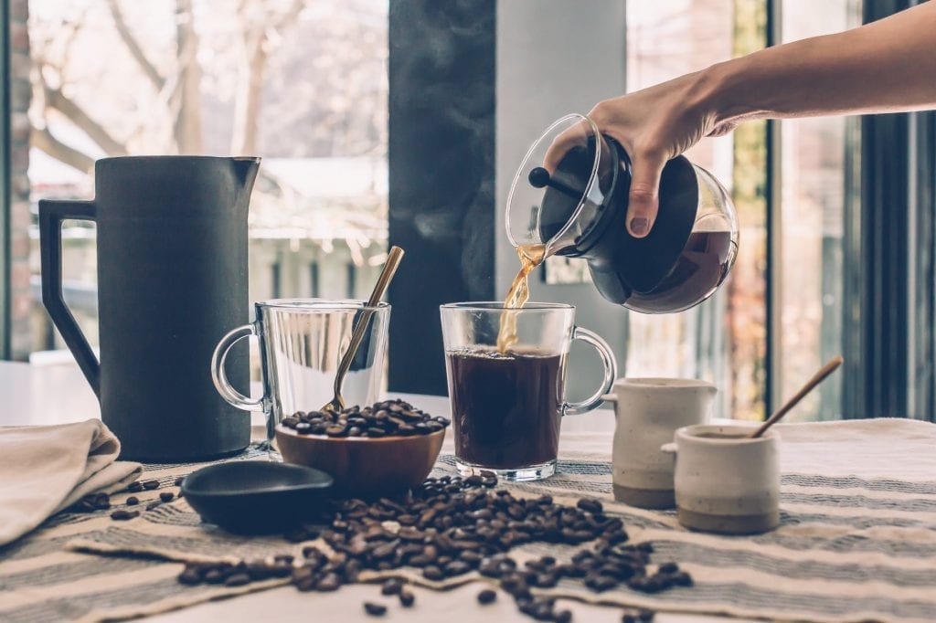 hand pouring over good morning coffee on a glass coffee mug