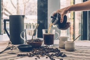 hand pouring over good morning coffee on a glass coffee mug