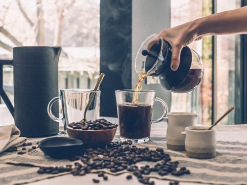 hand pouring over good morning coffee on a glass coffee mug
