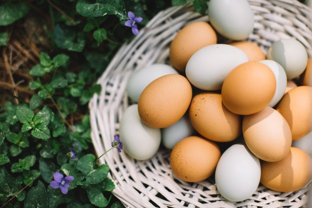 brown and white eggs inside a wooden basket