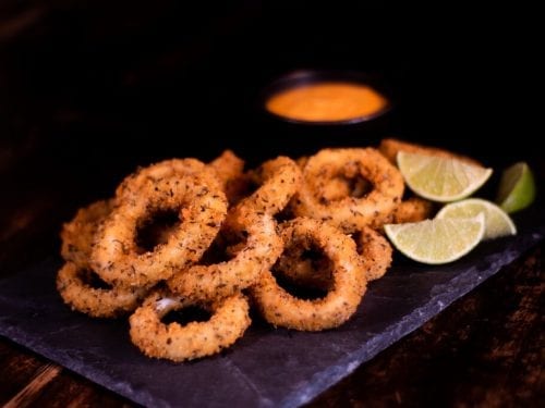 Calamari Fritti Recipe, fried calamari rings on a plate with lemon wedges and dip