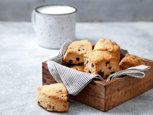chocolate chip scones in a wooden box, a mug of milk on a gray background