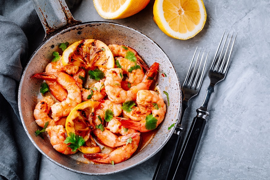 Spicy garlic chilli Prawns Shrimps on frying pan with lemon and cilantro