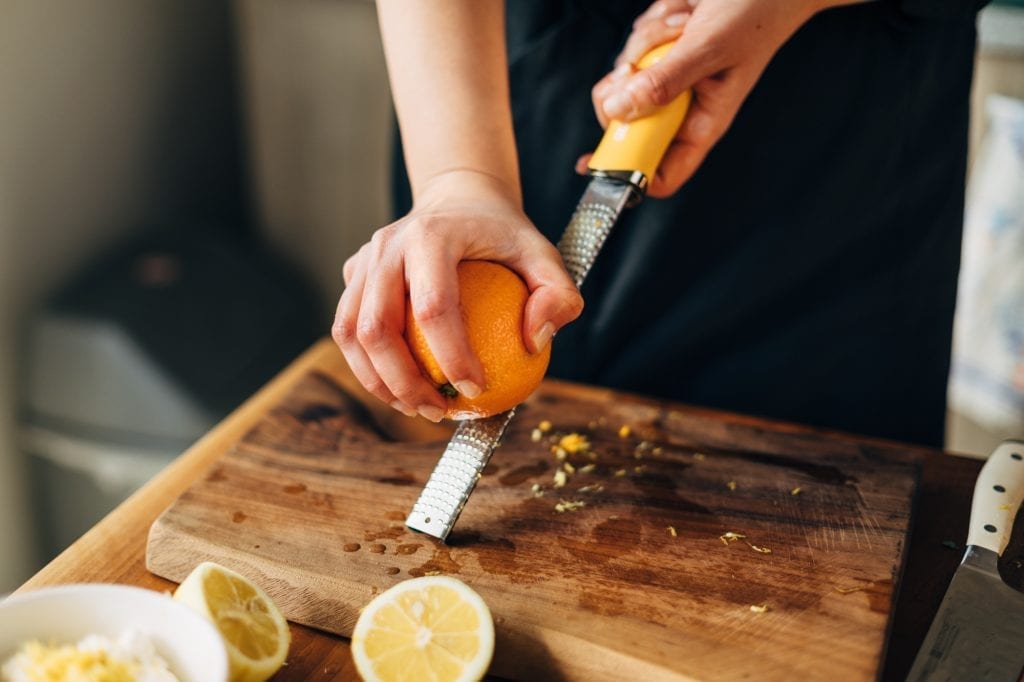 Person zesting an orange using a microplane