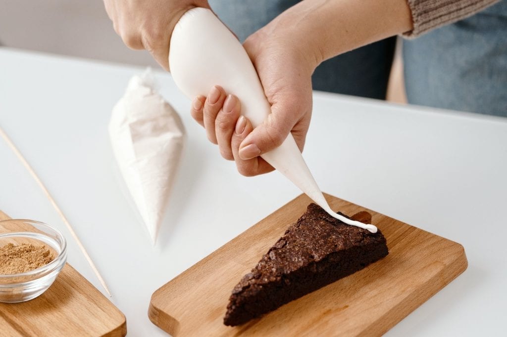 putting icing on a slice of pastry using a piping bag