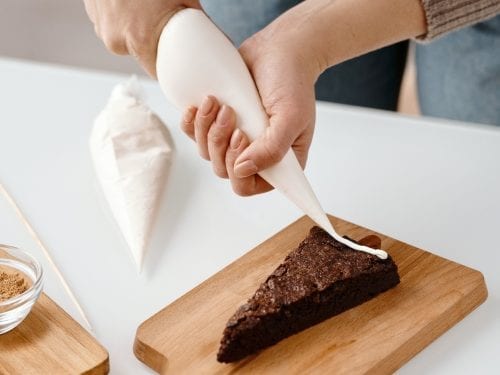 putting icing on a slice of pastry using a piping bag
